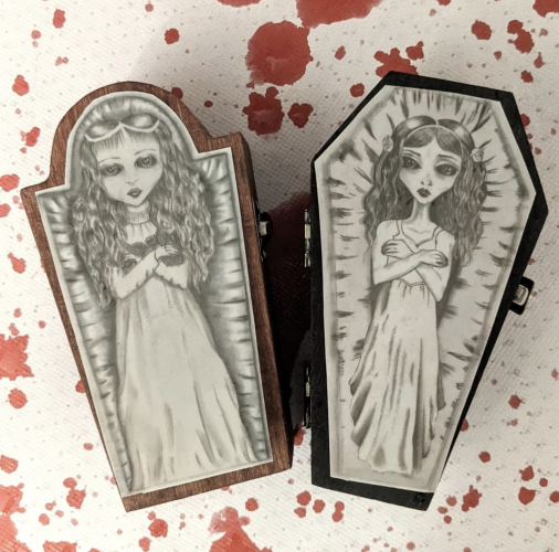 Two pencil drawings of vampire brides in wooden coffins.