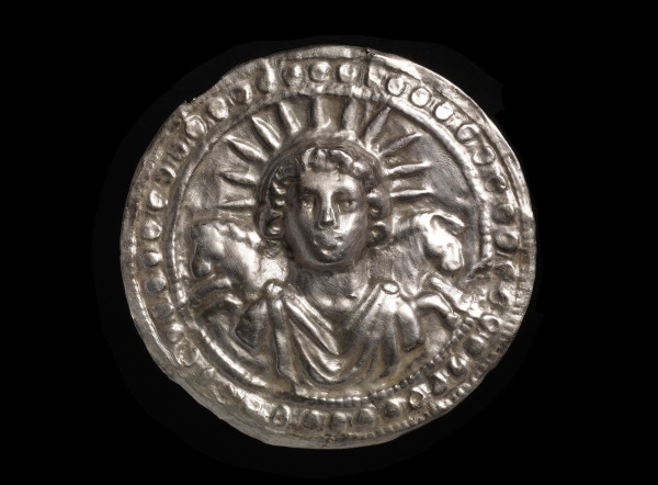Silver leaf disc depicting the Roman sun-god Sol. Sol is crowned with rays of light, and two horses appear behind his shoulders.