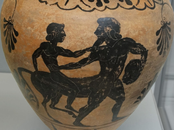 Black-figure vase painting suggested to be Achilles riding Chiron. The centaur is depicted with human front legs and a beard. A youth is riding on his equestrian back, possibly Achilles or any other of his numerous wards.