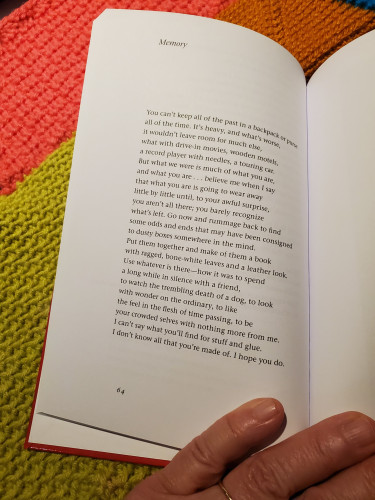 Poetry collection The Ways We Touch by Miller Williams, open to the poem "Memory", held against the backdrop of a multi-coloured afghan crochet work in progress

Memory

You can't keep all of the past in a backpack or purse
all of the time. It's heavy, and what's worse,
it wouldn't leave room for much else,
what with drive-in movies, wooden motels,
a record player with needles, a touring car.
But what we were is much of what you are,
and what you are ... believe me when I say
that what you are is going to wear away
little by little until, to your awful surprise,
you aren't all there; you barely recognize
what's left. Go now and rummage back to find
some odds and ends that may have been consigned
to dusty boxes somewhere in the mind.
Put them together and make of them a book
with ragged, bone-white leaves and a leather look.
Use whatever is there - how it was to spend
a long while in silence with a friend,
to watch the trembling death of a dog, to look
with wonder on the ordinary, to like
the feel in the flesh of time passing, to be
your crowded selves with nothing more from me.
I can't say what you'll find for stuff and glue.
I don't know all that you're made of. I hope you do.