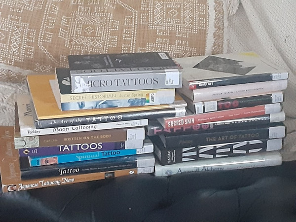 a giant pile of tattoo-related books on my couch, including (but not limited to):

micro tattoos by rayen
secret historian by spring
written on the body by caplan
maori tattooing by robley
the art of the tattoo by massacre
and
tatau: a history of samoan tattooing by galliot and mallon