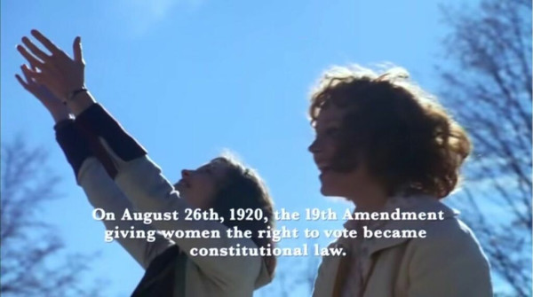 Two white women celebrate. The text on the screen reads "On August 26th, 1920, the 19th Amendment giving women the right to vote became constitutional law."