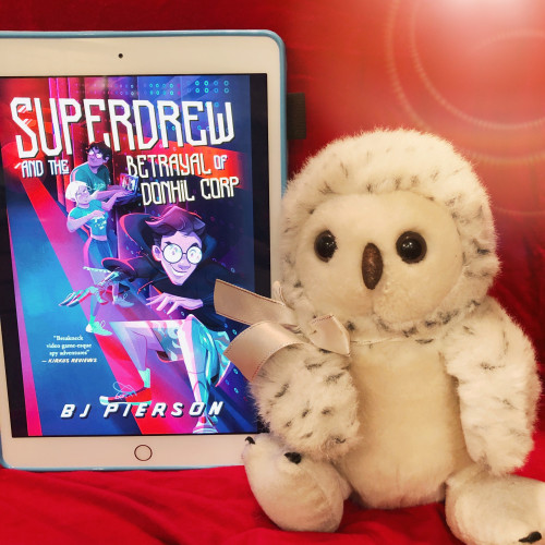 A photo of our spokes-owl Sylvia posing with the cover of SuperDrew and the Betrayal of Donhil Corp by BJ Pierson.