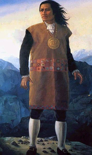 Painting of Tupac Amaru II, standing in front of mountains, wearing a brown tunic, with a medallion around his neck. By Unknown author - http://peru.feeder.ww7.pe/index.php?cal_date=2009-07-29, Public Domain, https://commons.wikimedia.org/w/index.php?curid=9105047