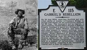 Road Sign commemorating Gabriel's Rebellion. To the left of the sign is a grainy image of Gabriel, sitting on a stool, wearing a cap.