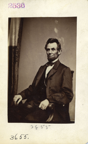 Famous black and white photo of Abraham Lincoln sitting in a chair.  