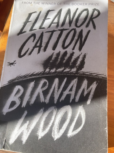 The black & white cover of Eleanor Catton’s Birnam Wood. Between her name & title is a horizon with silhouetted trees and a drone hovering next to them