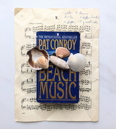 A piece of sheet music, the book, Beach Music by Pat Conroy, and some sea shells. 