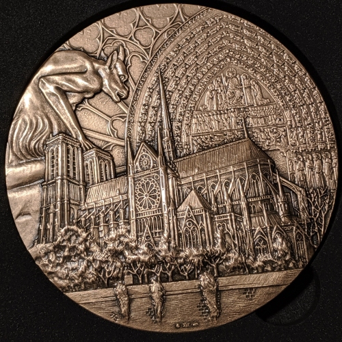The obverse represents the south facade of the cathedral. Tribute to the architecture of this famous monument. Inscribed are symbols of Gothic art: a gargoyle, the arch of the main entry and tympanum of Notre-Dame.