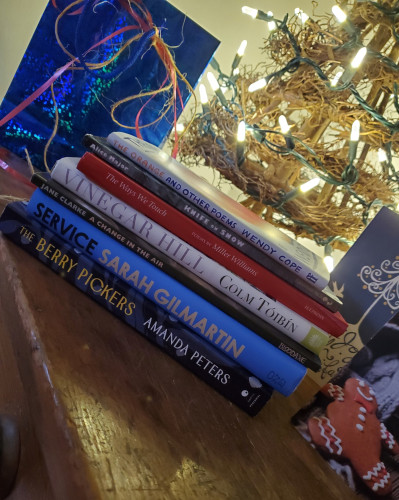 A stack of books next to a small, brightly lit twig Christmas trees and surrounded by hold cards - books by Wendy Cope, Alice Major, Miller Williams, Colm Toibin, Jane Clarke, Sarah Gilmartin, Amanda Peters