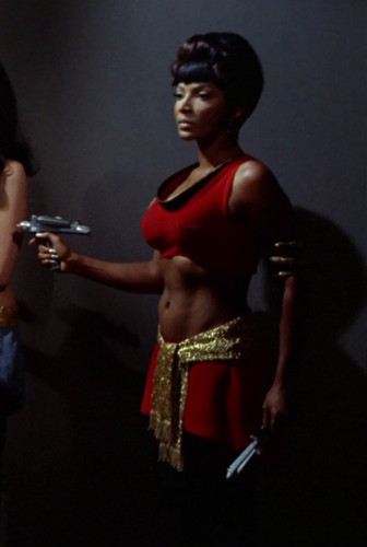 Uhura in amidriff baring uniform points a phaser.
