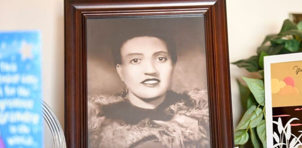 A framed, black and white photograph of woman rests atop a  table. 