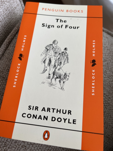 Penguin Books cover of The Sign of Four with Sherlock Holmes in familiar deerstalker hat and Doctor Watson following the trail of a dog.