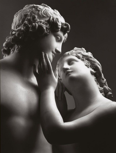 White marble statue of Adonis and Aphrodite. The goddess looks up at the handsome young man, giving his cheek a tender caress. He is looking lovingly into her eyes.