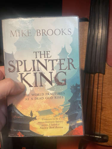 ‘The Splinter King’ by Mike Brooks being held up in front of a fretless bass guitar