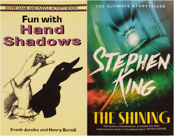 An image of two book photos, side by side.

On the left, a pale-yellow softcover with black text and illustrations —
DOVER GAME AND PUZZLE ACTIVITY BOOKS.
"Fun with Hand Shadows."
Frank Jacobs and Henry Bursill.
Across the top, two small decorative black bands run above and below the publisher branding, each band highlighted with a line of mauve dots. The bold letters of the title are outlined and drop-shadowed in black with mauve fill. An illustration of hands making a shadow of a duck on a nearby surface fills most of the cover. The author credits run below this, near the bottom edge.

On the right is a paperback with a hallway twisted counter-clockwise into the distance. The image is enhanced with a digital filter in the colors of the spectrum - a patch of red in the lower left tow mostly blue where the hallway ends in an open door, spilling white light.
Small white letters across the top proclaim, THE ULTIMATE STORYTELLER.
Large slashy white lettering fills the hallway with the name, STEPHEN KING.
Across the bottom of the book the colors have faded to solid black. The title, "THE SHINING," is in bold yellow above a small white blurb on two lines near the bottom,
'Obviously a masterpiece, probably the best supernatural novel in a hundred years' PETER STRAUB.

The overall arrangement of covers leaves the duck's shadow from the first book quacking at the author-name and image on the second book.