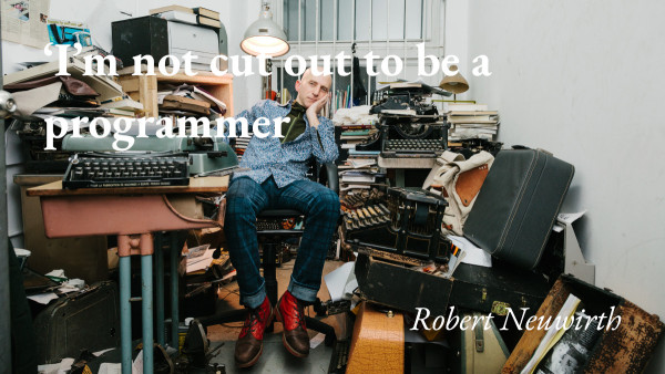 The writer Robert Neuwirth sits surrounded by mechanical typewriters and a quote from his podcast interview: 'I'm not cut out to be a programmer'