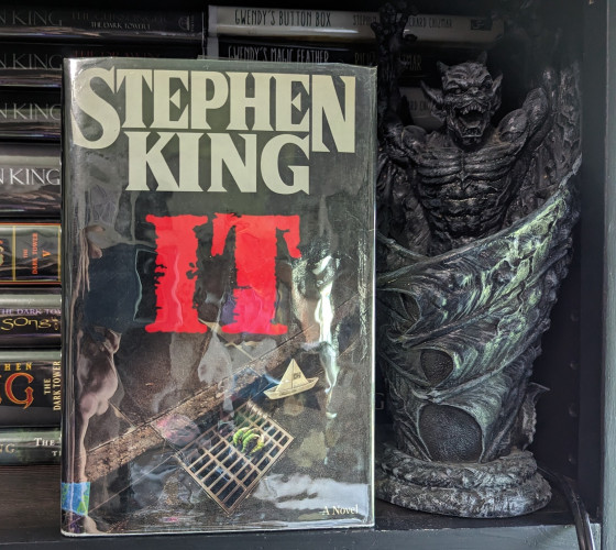 Hardcover first edition of Stephen King's IT.
A creepy reptilian claw emerges from a sewer grate, next to a paper sailboat.