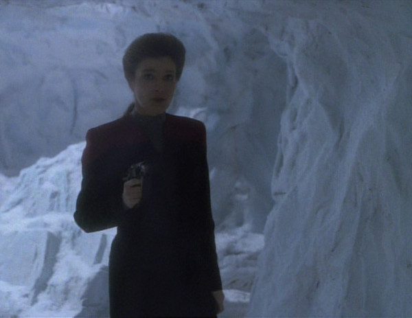 Janeway holding a pistol threatens an enemy.
