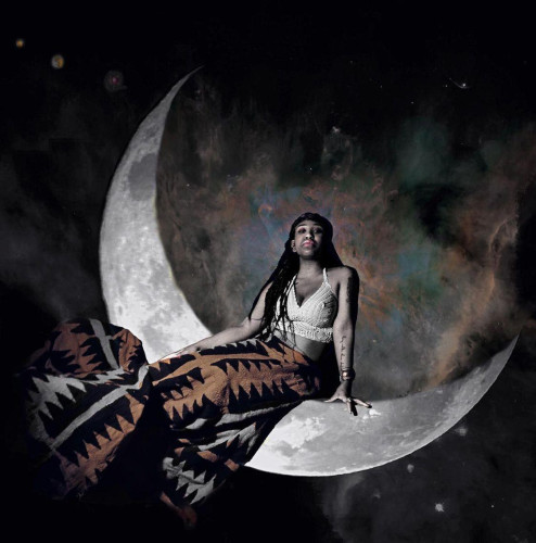 An androgynous black person sitting in a large lunar crescent wearing a white crop top and a patterned skirt in black, white, and orange." title="An androgynous black person sitting in a large lunar crescent wearing a white crop top and a patterned skirt in black, white, and orange.