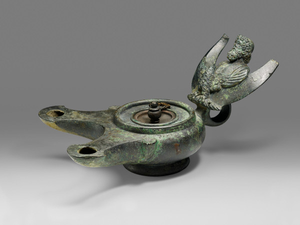 Description from the museum: “The handle of this lamp is adorned with a crescent moon surmounted by a bust of Jupiter, king of the gods, and his companion animal, the eagle, which clutches a thunderbolt (a symbol of the god) in its talons. A knobbed lid tops the container, which would have been filled with olive oil.”