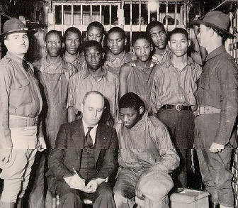 The Scottsboro Boys, with attorney Samuel Leibowitz, under guard by the state militia, 1932. Fair use, https://en.wikipedia.org/w/index.php?curid=21036733