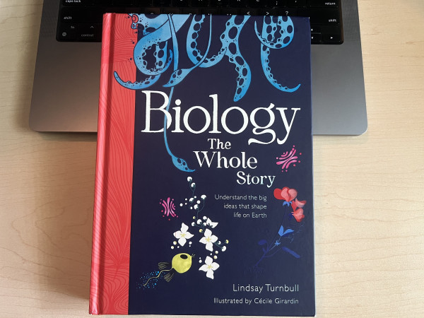 Cover of Biology the Whole Story (Understanding the big ideas that shape life on Earth) by Lindsay Turnbull and illustrated by Cecile Girardin. Cover has a red stripe on the left, and illustration of tentacles coming from the top, and pictures of flowers and other small creatures on the bottom.