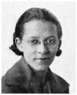Black and white photo of Beverly Lorraine Greene's senior portrait taken in 1935. She's wearing her hair smoothed back and curled under at the nape of her neck, wire frame glasses and a dark color jacked with wide collar in the style of that era. 