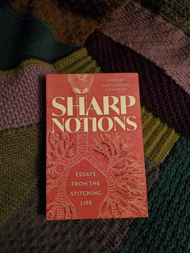 The book Sharp Notions - Essays from the Stitching Life, edited by Marita Dachsel & Nancy Lee (Arsenal Pulp Press), with its red and white cover showing an ornate stitched artwork, sits on a crocheted afghan assembled somewhat randomly of different earthy colours and textures. Contributors to the book include LJ Ahenda, Jenny Bartoy, Justina Chong, Laura Cok, Ciara Farmer, Anne Fleming, Tikenya Foster-Singletary, Danielle Geller, Lorri Neilsen Glenn, Jenny Judge, Theresa Kishkan, Sandra Lamouche, Rob Leacock, Carrianne Leung, Danielle Lussier, Bettina Matzkuhn, Sadiqa de Meijer, Lia Pas, Andrea Rexilius, Renee Sarojini Saklikar, Kevin Shaw, Elian Laslau Silverman, Jess Taylor, Kelly S. Thompson, Jan Wade, Kathleen Winter and Macayla Yan.