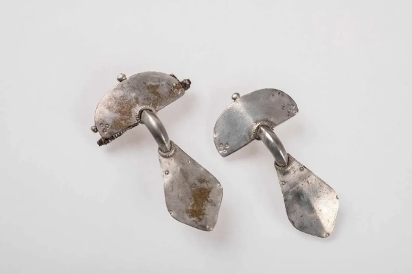 Two silver earrings against a white background. They are tear-drop shaped, flat and slightly angular, with a plate that covers the ear lobe.