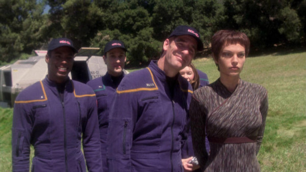 Archer, Travis and TPol in the foreground taking a picture in front of a shuttle pod after landing on an alien planet