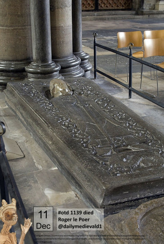 The picture shows a grave slab embedded in the ground. The outline of a bishop's figure is visible on the slab, the head protruding plastically