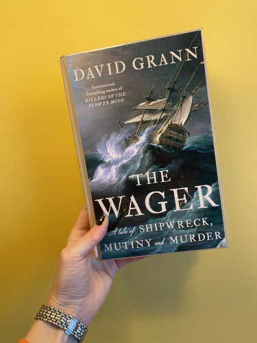 a photo of the book The Wager: A tale of shipwreck, mutiny and murder; by David Grann. on the cover we can see a 16th century ship during a storm, its balancing precariously on a big wave, it looks like the ship is about to fall on its right side (starboard?)