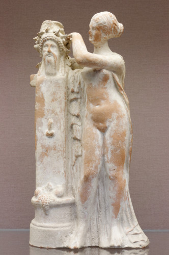 Terracotta figurine of Aphrodite in the nude crowning a herm of Dionysos.