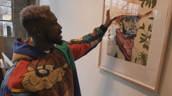 Otis Quaicoe showing artwork framed on wall of black cowboy