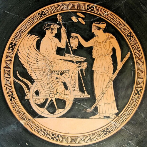 Red-figure vase painting of Triptolemos in Demeter's chariot drawn by two snakes or drakones. The youthful Triptolemos holds a bowl and receives water or wine from Demeter's daughter Persephone. Persephone can be identified by holding a torch towards the ground, a symbol of the underworld.