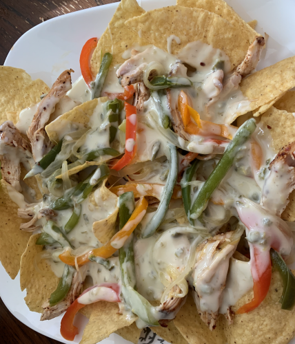 A plate of homemade nachos with chicken, queso blanco, and grilled onions and peppers