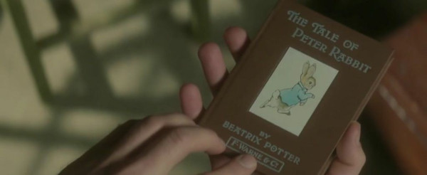 Hands holding a copy of a small book with an illustration of a rabbit on its cover, the Tale of Peter Rabbit by Beatrix Potter. 