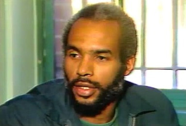 Screenshot of Kuwasi Balagoon during a television interview conducted in the mid-1980s. He has a trim beard and mustache, with graying, receding hair. By WPIX - Original publication: New York, mid 1980sImmediate source: https://www.youtube.com/watch?v=bWn2B881BuQ&amp;ab_channel=LibraryMachineBroke, Fair use, https://en.wikipedia.org/w/index.php?curid=67132755