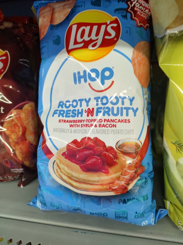 Photo of a bag of Lays potato chips. They are flavored: "IHOP ROOTY TOOTY FRESH 'N FRUITY STRAWBERRY-TOPPED PANCAKES WITH SYRUP & BACON"

WHY HAPPENING