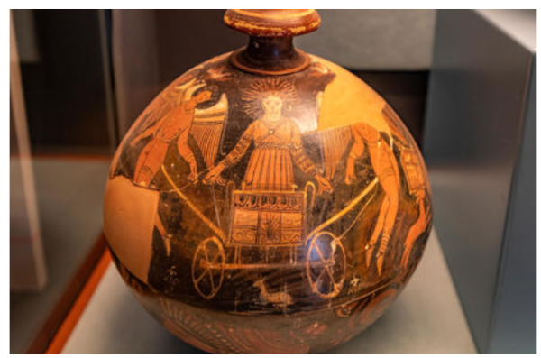 Red-figure vase painting of Helios in a chariot drawn by two naked Erotes ("Loves"). Helios is dressed in a long, sleeved chiton with elaborate patterns and his hair is forming an aureola around his head.