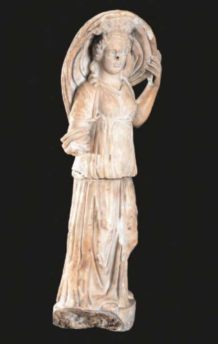 Sculpture of Selene carved from a cylinder of coarse-grained marble. It shows no traces of reworking. The right hand, which may have held a torch, is missing, while the inscription on the base is probably modern. The figure wears a chiton with short sleeves, a long peplos fastened at the shoulders and a double belt at the waist. A large cloak, held by the right arm and stopped by the left hand, passes behind the back and swells around the head. The lunar crescent emerges clearly from the shoulders, identifying the sculpture with the personification of Selene, goddess of the Moon. The left hand and arm are disproportionate, excessively conditioned by the main point of view, which had to be from the right, in the direction of the deity's gaze. The figure represents the personification of Selene as she descends to earth in her chariot to meet Endymion, which would justify the swelling of the cloak that haloes her head. This iconography of the divinity can be found on Roman sarcophagi with the depiction of the Endymion myth in relief on the forehead, which were widespread from the first half of the 3rd century CE and of which numerous specimens are preserved. It is not excluded that the statue adorned a sanctuary, perhaps a domestic one. Moreover, it should not be forgotten that the iconography of Selene with the moon behind her back also appears on reliefs for the cult of Mithras, worshipped in Rome around 1 BCE and spreading between the 2nd and 3rd century CE.