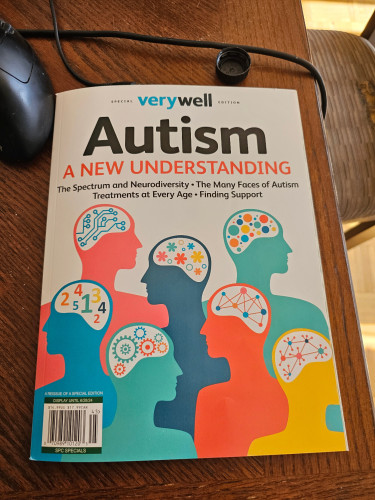 A magazine with cartoon silhouettes of people with colourful gears, numbers and other symbols inside their heads. The headline reads "Autism: A New Understanding"