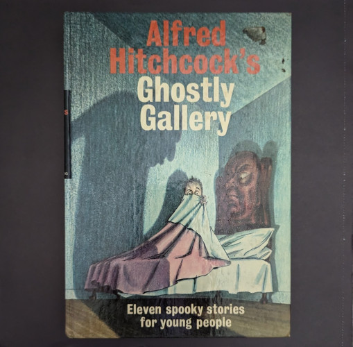 Alfred Hitchcock's Ghostly Gallery. An illustration of a boy in bed clutching his blankets up to his face is on the cover. The bedframe has a face in it and a sinister shadow looms over him on the wall.
