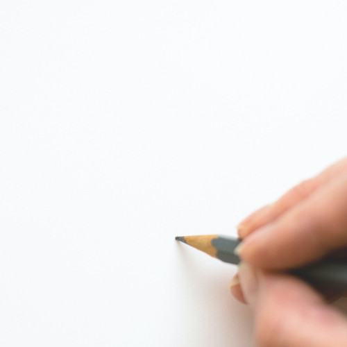 Close up of a person's finger tips holding a pencil and press it on to a blank page