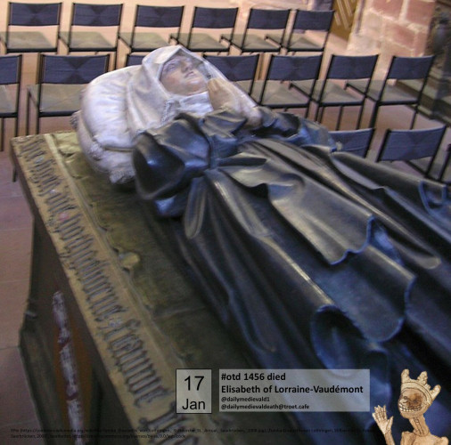 The picture shows a grave slab with a plastic reclining figure. The figure is female, dressed in a blue robe with a white veil and has her hands folded in prayer.