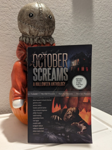 Cover of OCTOBER SCREAMS anthology perched in front of Sam from Trick 'r Treat