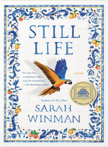 The ebook cover of Still Life by Sarah Winman. A large yellow and blue parrot spreads his wings in the middle. The background is white Italian tile; along the borders the tile is decorated with a blue floral and leaf motif, with citrus fruits.