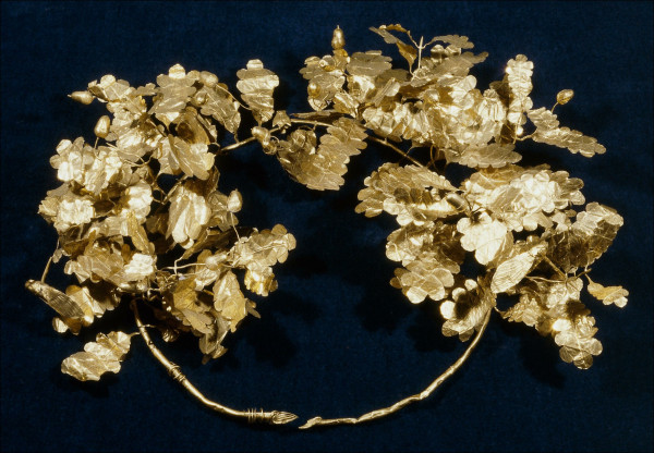 Description from the museum: “Gold oak wreath with a bee and two cicadas. This wreath consists of two branches. At the back the stems have obliquely cut end-plates; at the front the two branches are held together with a split pin fastener that has a bee as its cap. The branches are made of sheet-gold tubes, over a modern copper core. Each branch has six sprays with eight leaves and seven or eight acorns, as well as a cicada. In addition, there are about a dozen single leaves set straight into each branch. The leaves are of three different sizes and are made in one piece with their stalks. The acorns are made in left and right die-formed halves; the cups are cross-hatched and there is a point on the top of the fruit. The cicadas are constructed from four separate sheets of gold - lower body, upper body, two wings.”