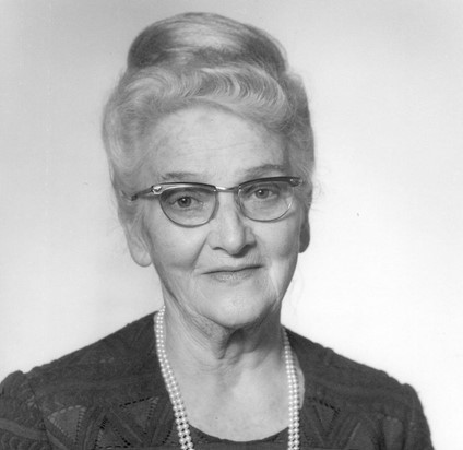 Marie Laeng-Stucki in later life, head and shoulders black and white photo. White woman looking direct at camera with slight smile, light hair piled on top of head, glasses, dark dress double string of pearls